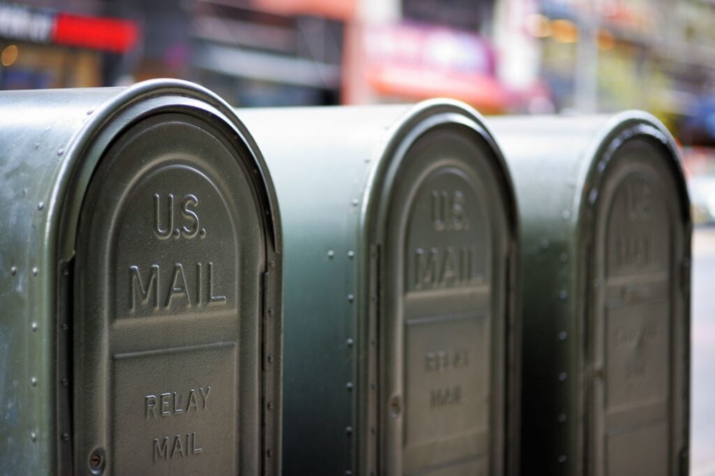 Row of green US Mail relay collection boxes on a city street