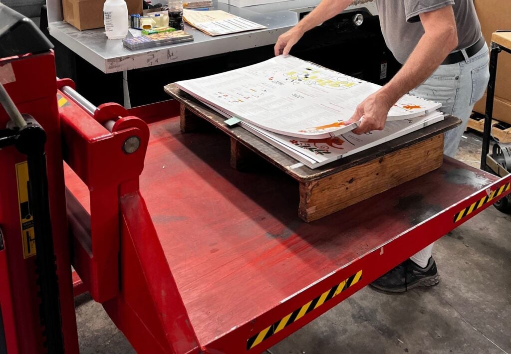 MPress operator checking a printed sheet on a red proofing press