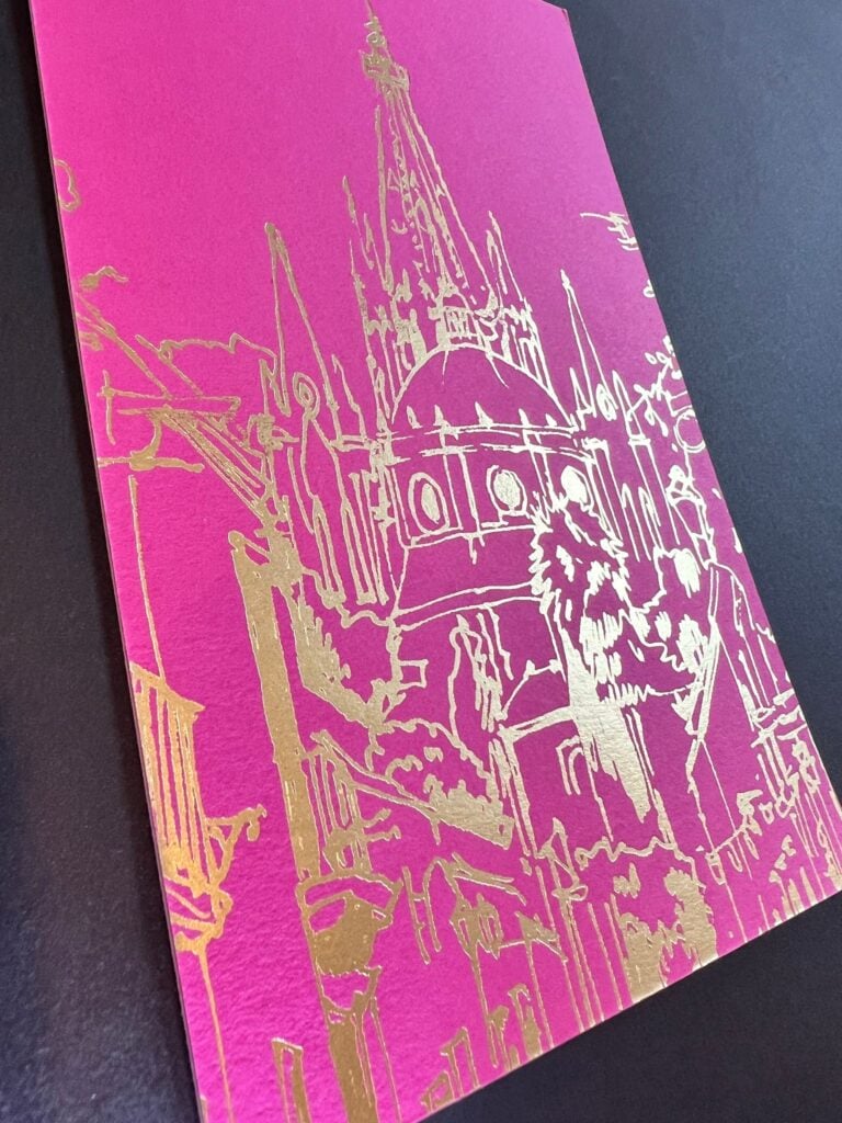 Hot pink invitation printed with a gold foil illustration of a New Orleans cathedral