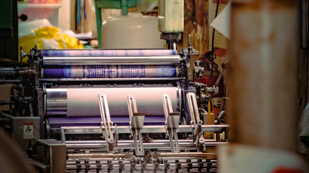 Offset press ink train with a stack of colored rollers running ink down to the plate