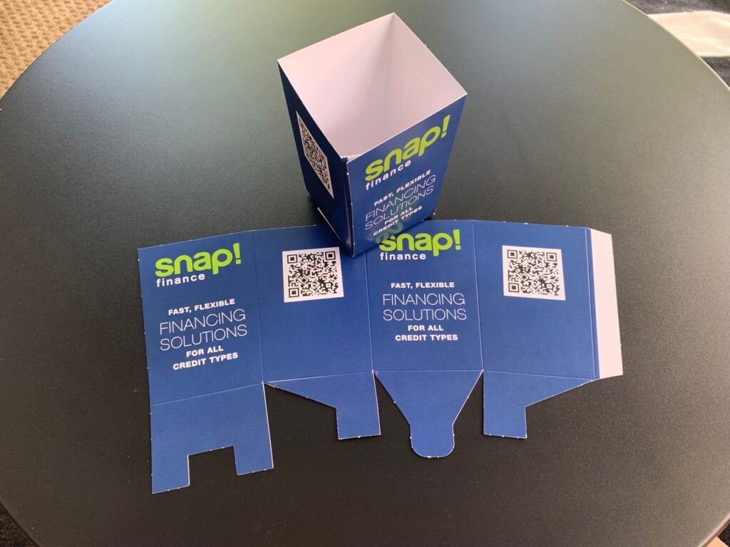 Snap Finance point of sale display carton shown as a flat die cut blank and assembled, printed with a QR code